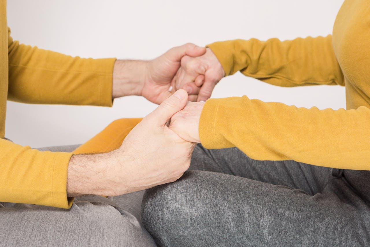 A close-up of two adults holding hands in a gesture of support and love.